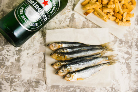 Ukraine, Chernihiv, June 24, 2023: Flatlay, beer, fish and crackers on a light background
