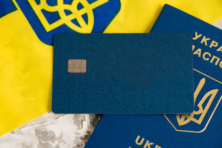 Flatlay, flag of Ukraine, passport and bank card on a light background.