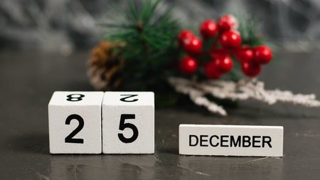 Wooden calendar with December 25 date and beautiful Christmas decoration on dark textured background with copy space.の写真素材