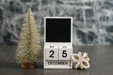 Wooden calendar with December 25 date and beautiful Christmas decoration on dark textured background...