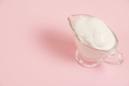 White sauce in a glass saucer on a pink background.の写真素材