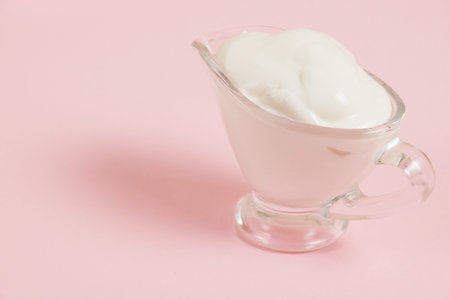 White sauce in a glass saucer on a pink background.の写真素材