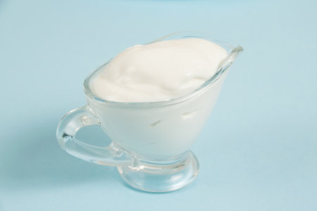 White sauce in a glass saucer on a blue background.の写真素材
