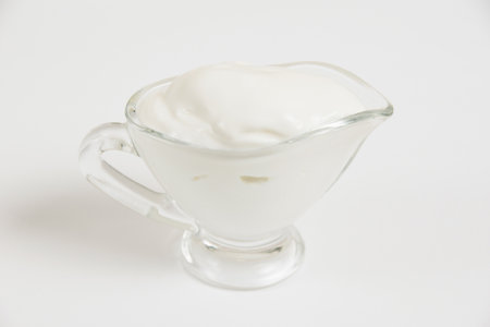 Sour cream in a glass saucer on a white background.の写真素材