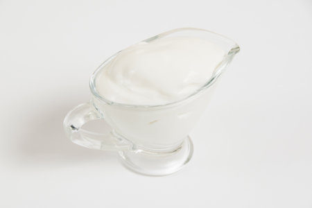 Sour cream in a glass saucer on a white background.の写真素材
