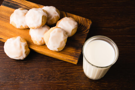 Glass of milk and delicious homemade gingerbread cookies with honey and cinnamon on dark wooden background with copy space flatlayの写真素材