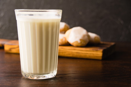 Glass of milk and delicious homemade gingerbread cookies with honey and cinnamon dark wooden background with copy spaceの写真素材