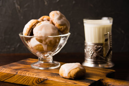 Homemade gingerbread cookies with honey, cinnamon and vanilla in a glass bowl and a glass of hot milk on a dark background.の写真素材