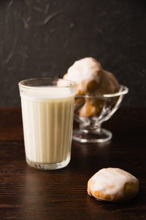 Delicious homemade gingerbread cookies with honey, cinnamon and vanilla in a glass bowl and a glass of hot milk on a dark background.の写真素材