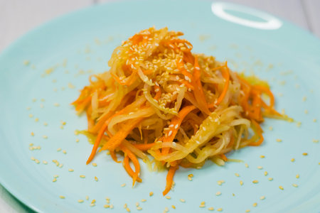 Delicious Korean cuisine. Salad with carrots and daikon Korean style on a beautiful turquoise plateの写真素材