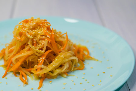 Delicious Korean cuisine. Salad with carrots and daikon Korean style on a beautiful turquoise plate