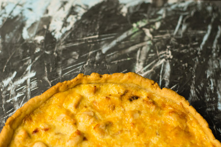 Flatlay, portion of delicious French quiche pie with chicken and cheese on dark background with...