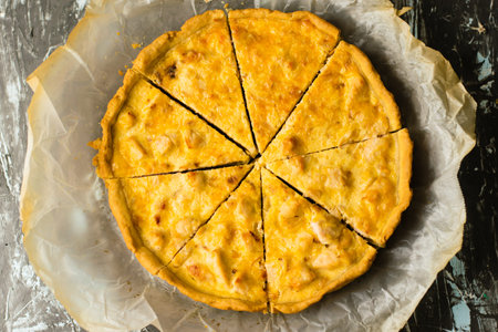 Delicious French quiche pie with chicken and cheese. Baking process pie cooling on baking parchment