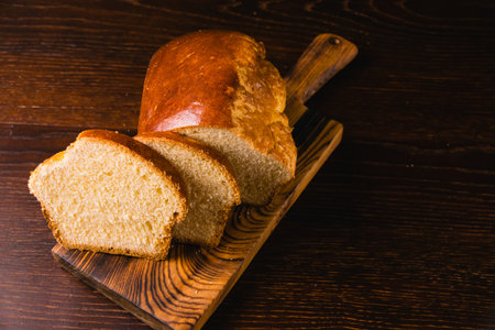 Delicious and sweet buttery bread cut into slices on dark wooden cutting board. Delicious home baked goodsの写真素材