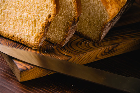 Delicious and sweet buttery bread cut into slices on dark wooden cutting board. Delicious home baked goodsの写真素材