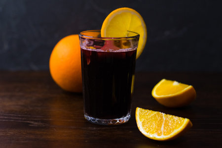 Mulled wine with orange, cinnamon and honey in a glass on a dark background. Concept of a cozy winter evening, Christmas and New Year celebration.の写真素材