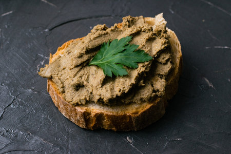 Healthy food, sandwich with liver pate, parsley and baguette on a dark background.