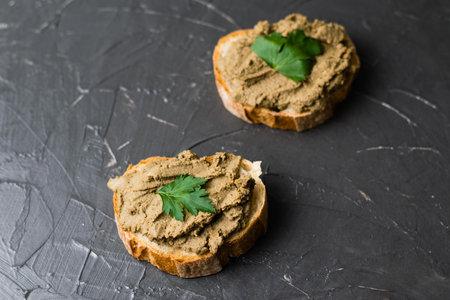 Healthy food, sandwiches with liver pate, parsley and crispy baguette close-up on a dark backgroundの写真素材