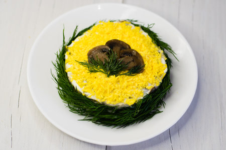 Delicious holiday salad with champignon mushrooms, eggs, canned green peas, mayonnaise and dill on a white plate on a light background with copy space.の写真素材