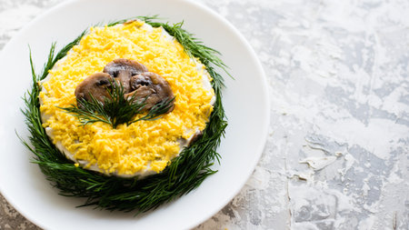 Delicious holiday salad with champignon mushrooms, eggs, canned green peas, mayonnaise and dill on a white plate on a light background with copy space.の写真素材