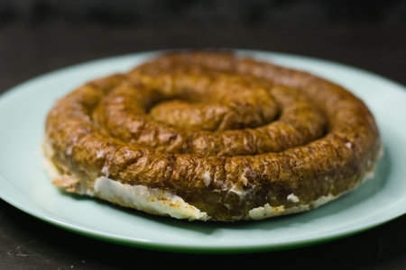Delicious baked homemade sausage on a plate on a dark background, preparation for celebrating Easter in the family.の写真素材