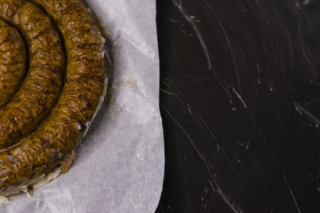 Delicious baked homemade sausage on non-stick baking paper on a dark background, preparation for celebrating Easter with the familyの写真素材