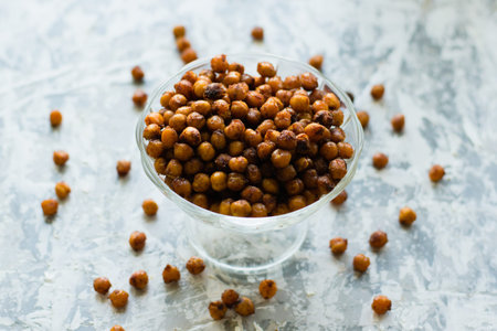 Delicious baked chickpeas in a transparent bowl on the table, on a light background with space for...