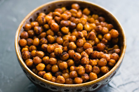 Delicious snack, fragrant baked with spices chickpeas in a brown bowl on a dark background with space for text. Healthy eating conceptの写真素材