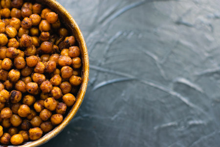 Delicious snack, fragrant baked with spices chickpeas in a brown bowl on a dark background with space for text. Healthy eating conceptの写真素材