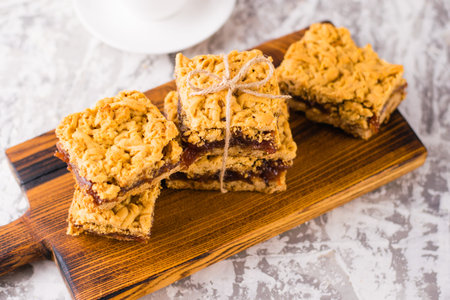 Delicious homemade pie with apple jam. Appetizing slices of grated pie with jam on a wooden board and coffee in a white cup on a light table.の写真素材