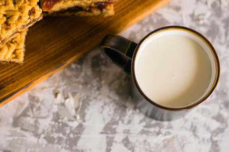 Delicious homemade pie with apple jam. Appetizing slices of grated pie with jam on a wooden board and a cup of milk on a light table.の写真素材