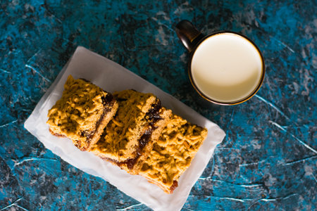 Delicious homemade pie with apple jam. Appetizing slices of gratified pie with jam on a wooden board and a cup of milk on the table flatlayの写真素材