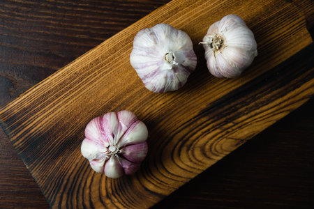 Cloves of unpeeled garlic close-up on a dark wooden table.