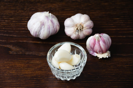 Garlic cloves close-up on a dark wooden table. Concept of cooking and village life.
