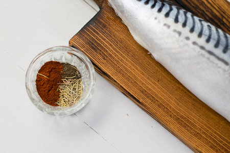 Raw mackerel fish on a cutting board, cooking fish with salt, spices and sauce