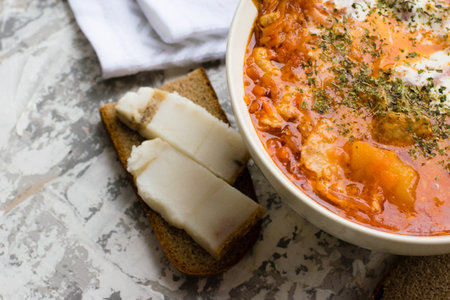 Delicious and aromatic red soup with meat, Ukrainian borscht with sour cream, dill and pieces of lard on bread. Traditional Ukrainian dish, cuisine.の写真素材