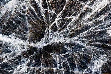 Cracked ice close-up. Frozen water, ice on brown paving stones.