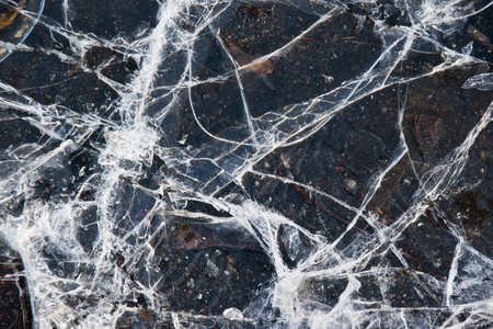 Cracked ice close-up. Frozen water, ice on brown paving stones.