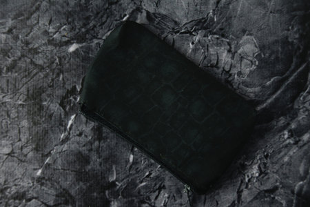Old black wallet on dark textured stone background