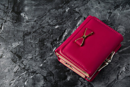 Bright women's wallet on dark textured stone background with copy space
