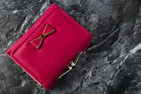 Bright women's wallet on dark textured stone background with copy space
