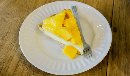 Mango pie on white dish with silver fork put on wooden tableの写真素材