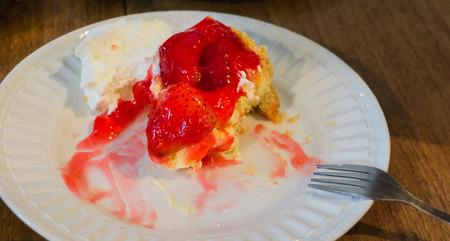 Strawberry shotcake on white dish with silver fork putting on wooden tableの写真素材