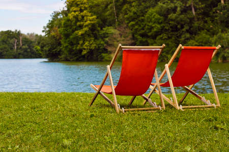 Two orange sun beds on the lake in the woodsの写真素材