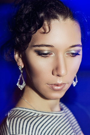 Young beautiful girl with a New Year's make-up on New Year's party. Portrait of a girl in blue lights. New Year's Eve 2016.の写真素材
