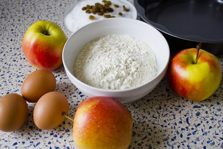 Ingredients for apple pie on the kitchen table. Flour, sugar, raisins, eggs and apples for homemade pastries.の写真素材