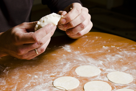 Man's hands preparing dough for ravioli, tortellini. Making baking.の写真素材
