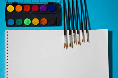 Still life with a set of watercolor painting. Paints, brushes and watercolors for the album on a blue background.の写真素材