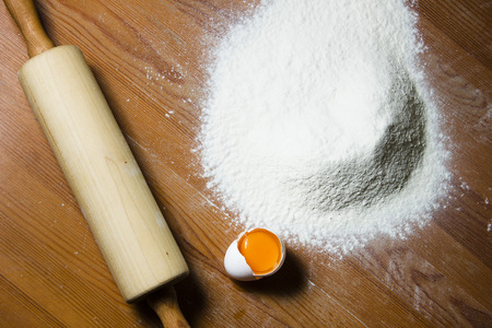 Ingredients for cooking dough on a wooden table. Flour, egg and a rolling pin.の写真素材