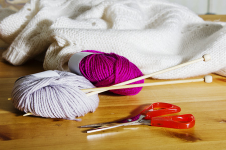 Knitting accessories on a wooden table. Balls of wool and wooden knitting needles on the table.の写真素材